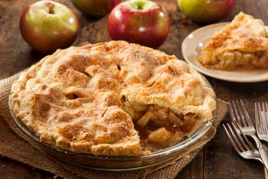 dish of apple pie with one slice taken out on a plate to the side