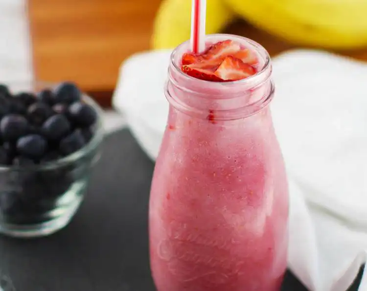 berry smoothie with a bowl of blueberries on the side