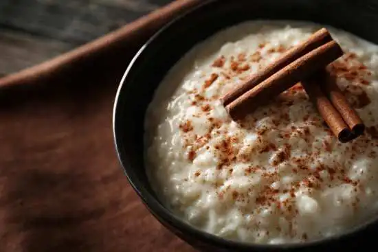 bowl of rice pudding with cinnamon sticks on top