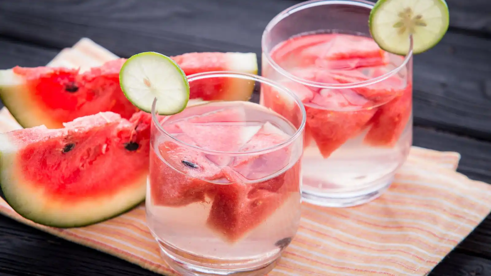 glasses of water with watermelon chunks in them and sliced watermelon to the side