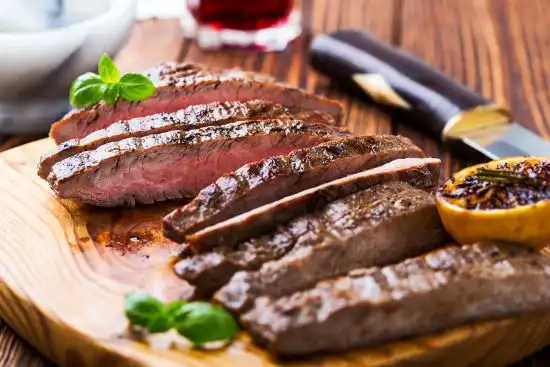 cutting board with herb broiled beef sliced