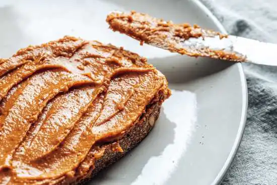 slice of bread with peanut butter and a spreading knife next to it
