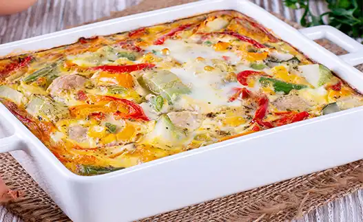 large white baking dish of polenta with peppers and cheese