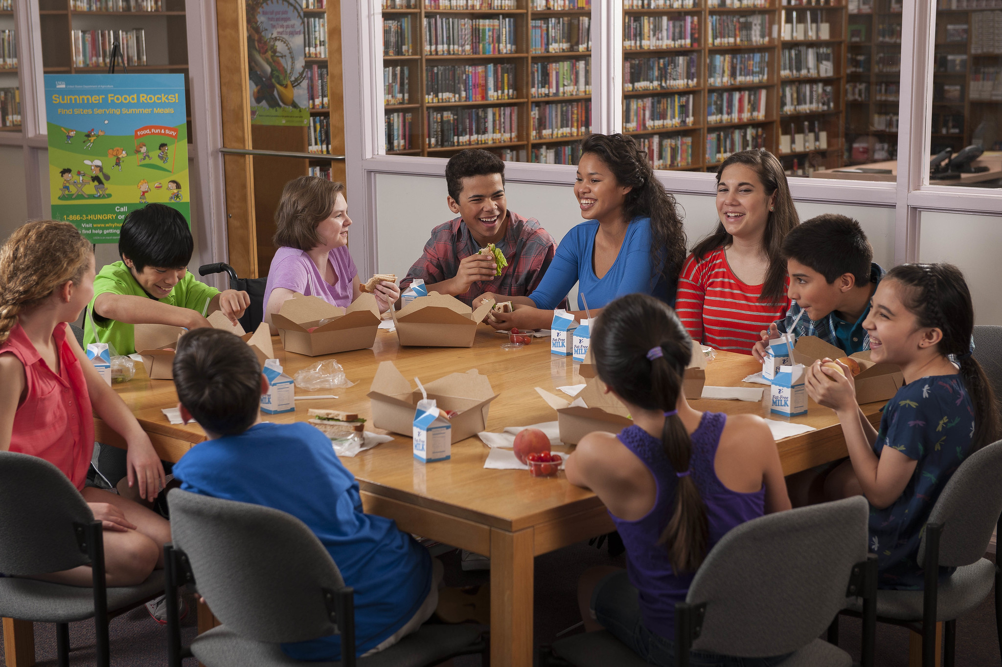 A group of school-aged children sitting around a table eating lunch together.