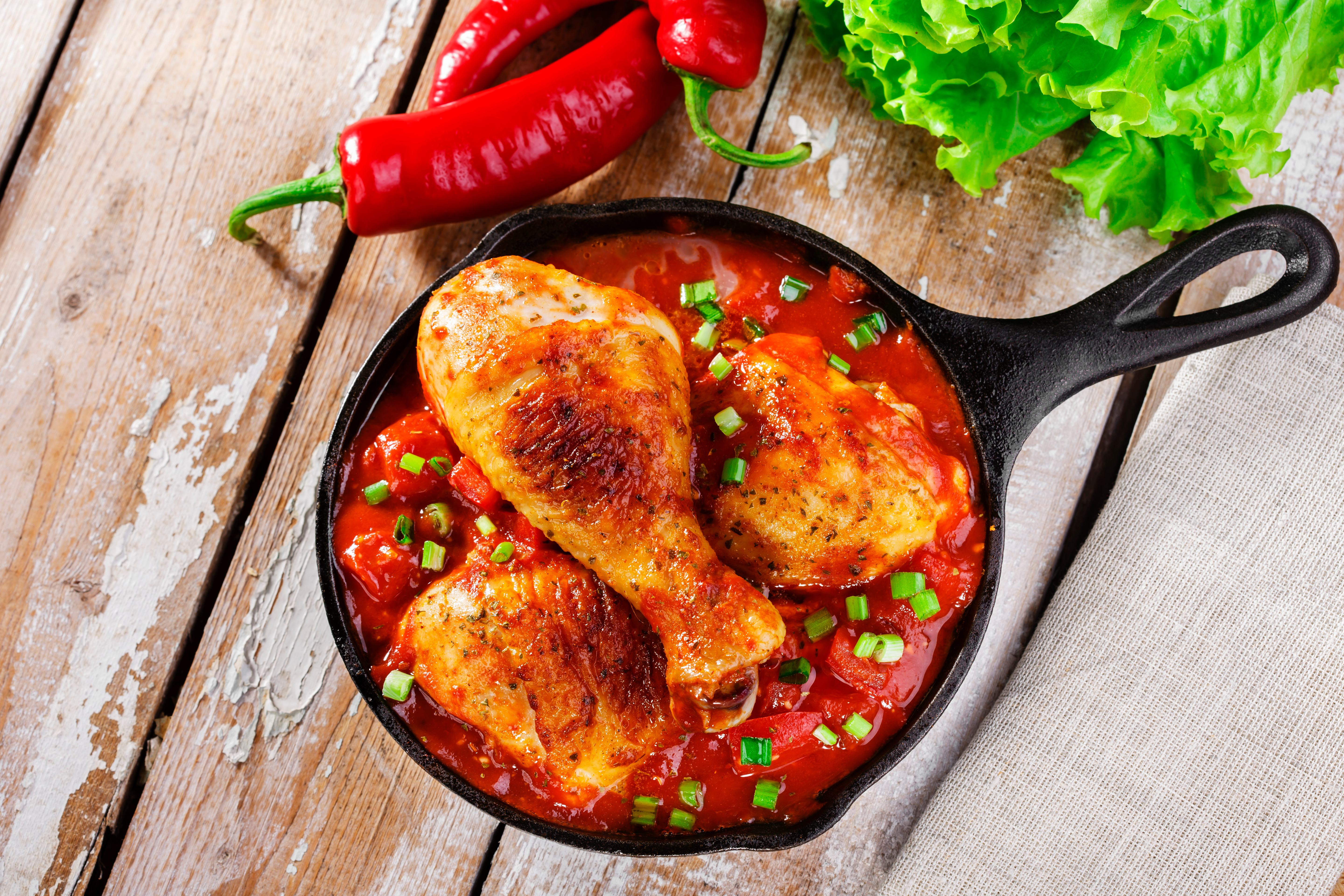 a cast iron skillit with chicken drumsticks in a red sauce