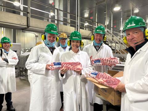 Secretary Rollins and staff at Cargill Bioscience Complex holding meat products and wearing green helmets and white lab coats.
