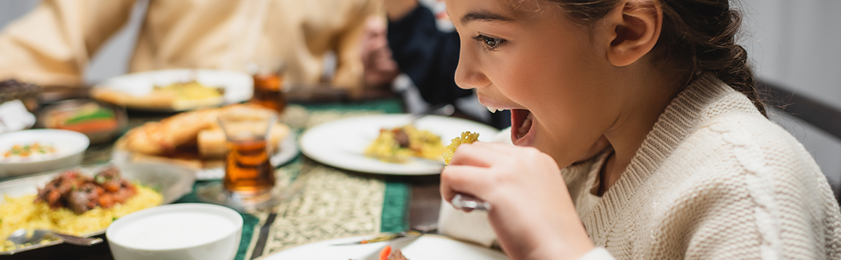 young girl eating dinner with her family