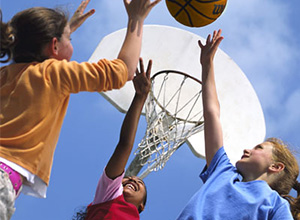 3 kids jumping for a basketball in front of a hoop