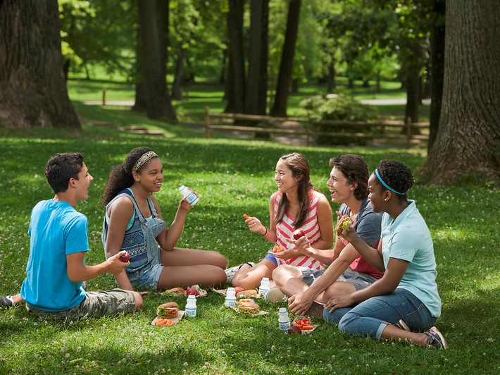 kids enjoying a summer meal on a green lawn