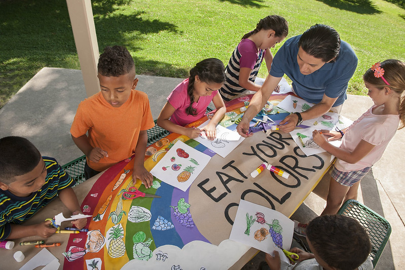 Students creating a colorful mural with fruits and vegetables