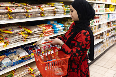 woman wearing a hijab shopping for WIC foods and putting lentils in her basket