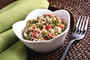 bowl of grains with tomatoes, cucumbers and other ingredients