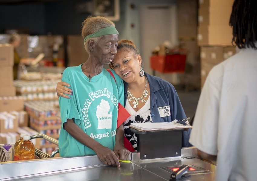 two women hugging at a grocery check-out line