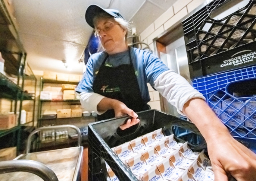 school nutrition professional carrying a carton of milk in a walk-in cooler
