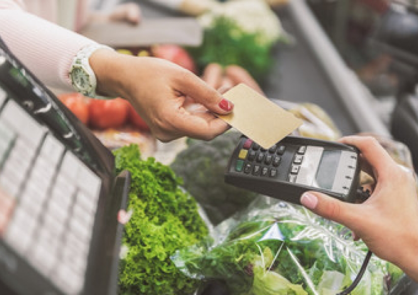 a person swiping their card on a card reader at a grocery store checkout line