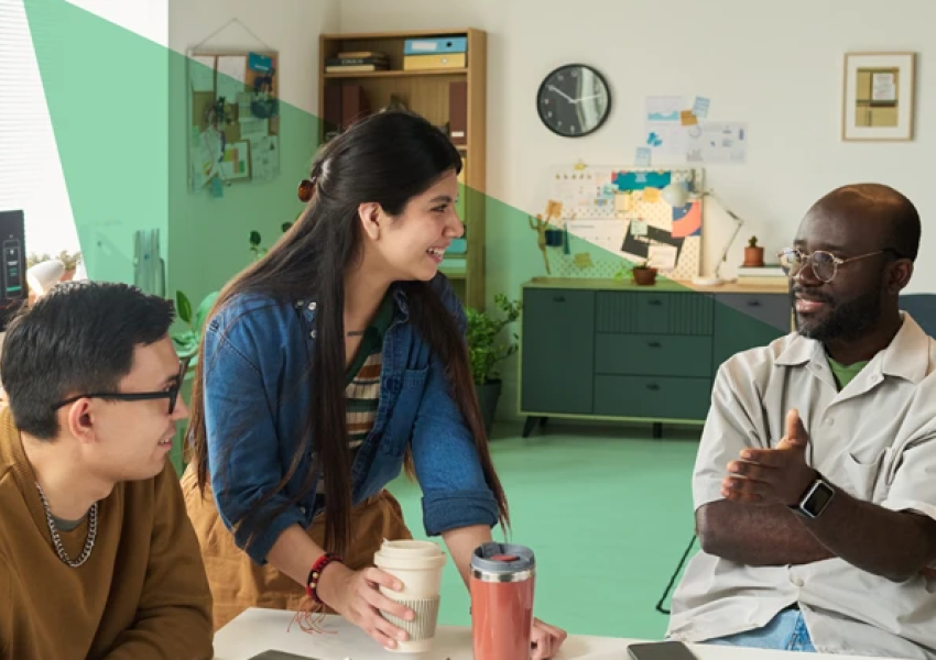 3 people talking with coffee cups around a table 
