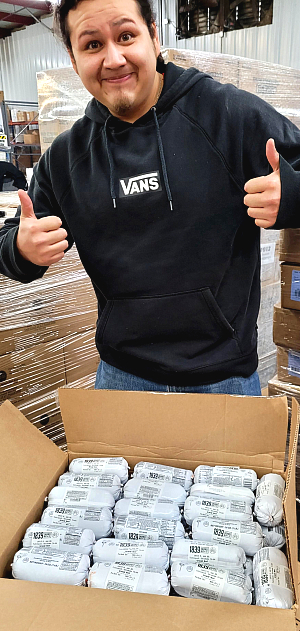 young man giving two thumbs up over a packed box of ground beef