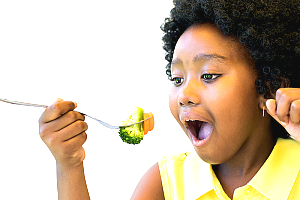 Girl eating broccoli and carrots