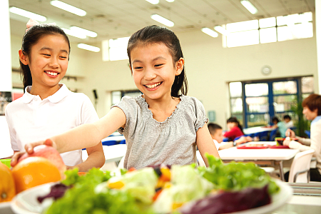 students eating vegetables from a salad bar at school lunch.