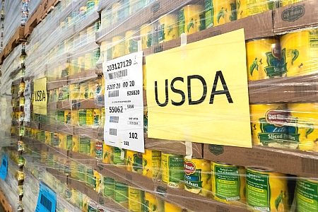 a pallet of canned sliced peaches with a yellow USDA sign