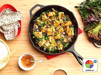 photo of turmeric fish dish prepared in a cast iron skillet with a side salad and dipping sauce