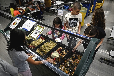 students serving themselves from a salad bar in a school cafeteria