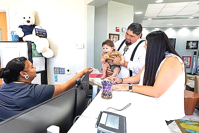 a family with their toddler at a wic clinic being greeted at the desk