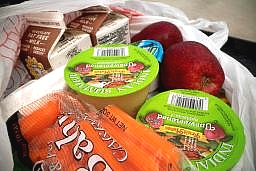 a bagged school lunch with applesauce, apples, milk, and baby carrots